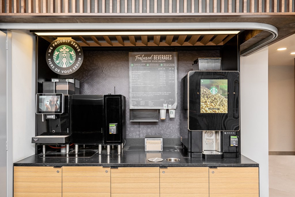 a counter with coffee machines and a menu on the wall