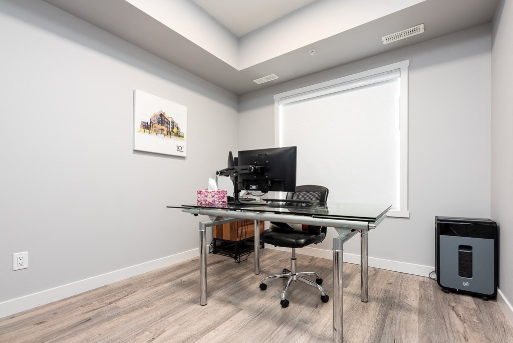 a home office with a computer on a desk and a window
