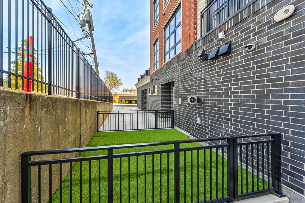 A black metal fence surrounds a green lawn.