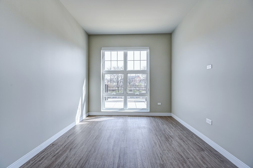 A room with a large window and wooden flooring.