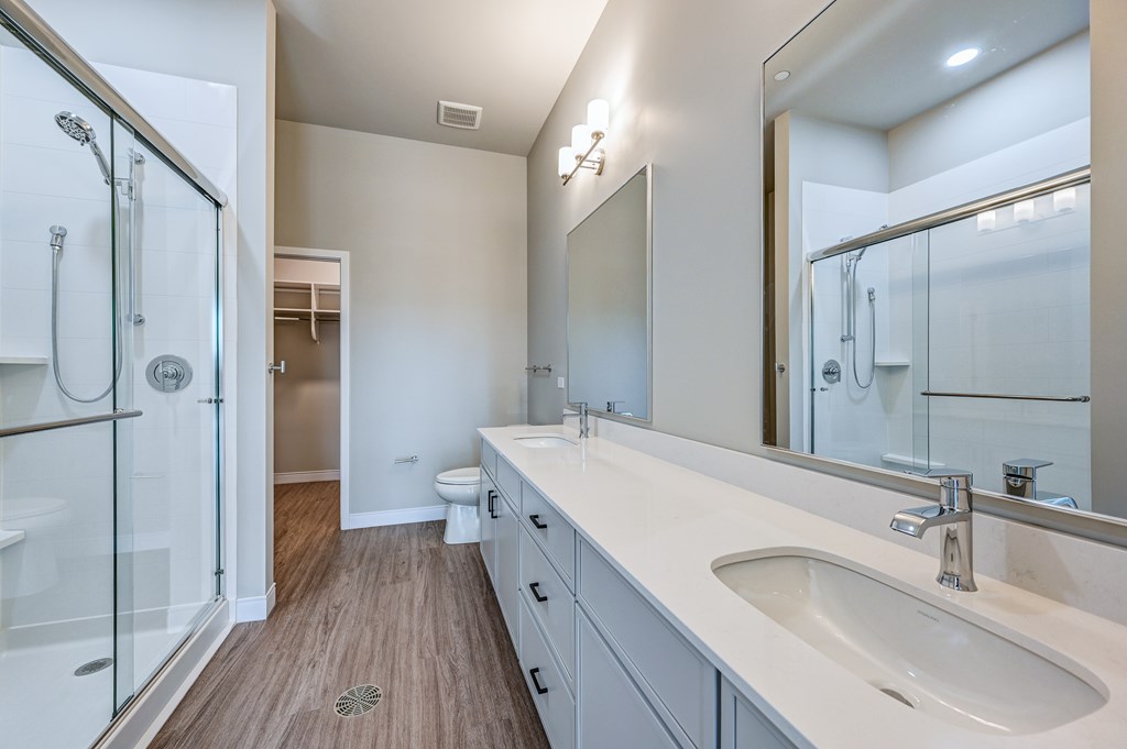 A modern bathroom with a walk-in shower and double sinks.