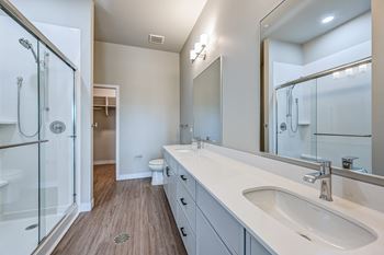A modern bathroom with a walk-in shower and double sinks.
