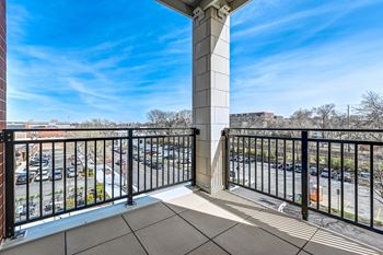 A balcony with a black railing and a concrete pillar.