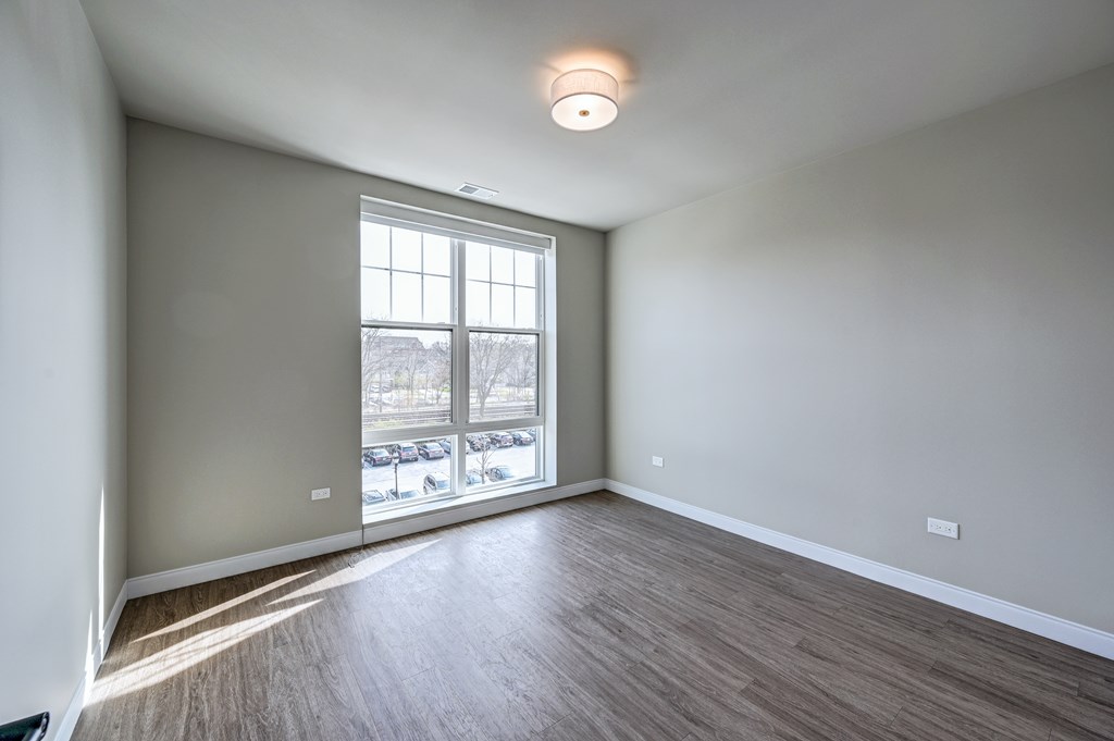 A room with a large window and wooden flooring.