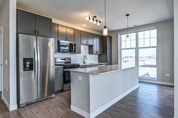 A modern kitchen with a refrigerator, microwave, oven, and sink.
