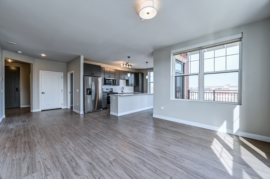 A spacious kitchen with wood flooring and a large window.