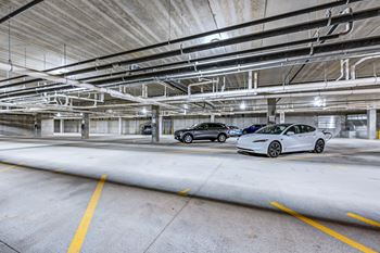 A white Tesla car is parked in a parking garage.