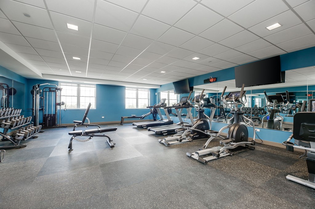 a gym with weights and cardio equipment in a building with blue walls