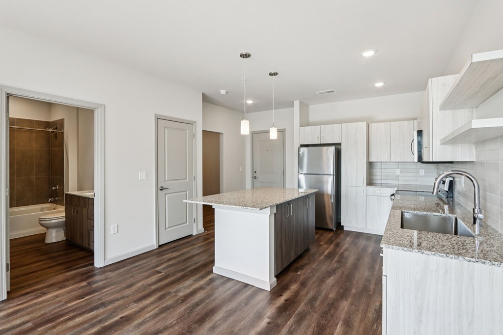 A modern kitchen with white cabinets and a wooden floor.
