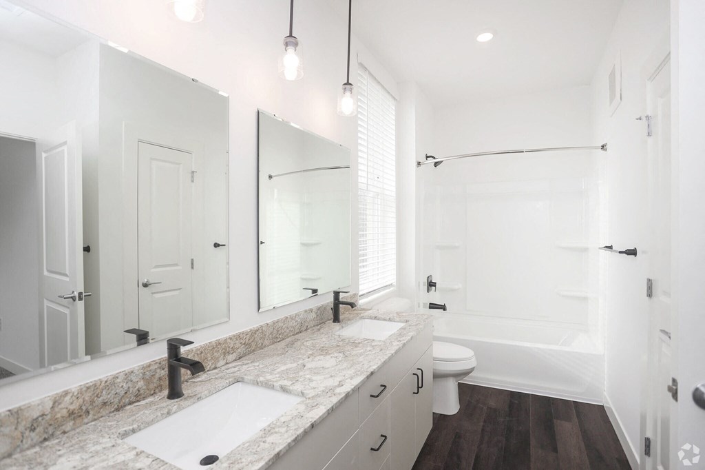 a bathroom with a double vanity sink, toilet, and bathtub