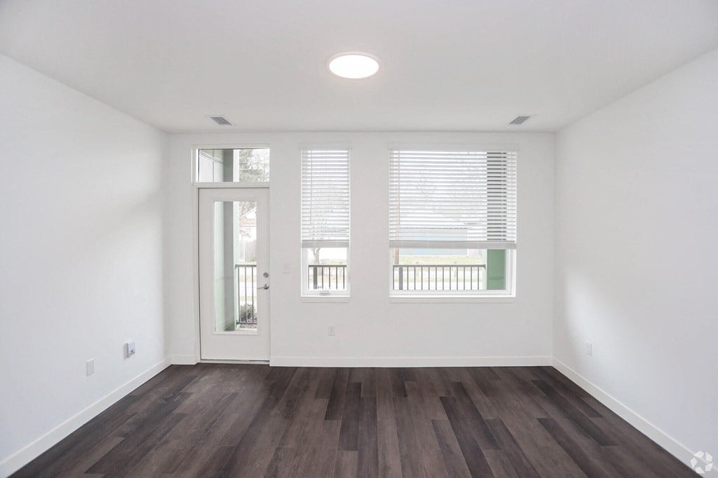 an empty living room with large windows and natural light
