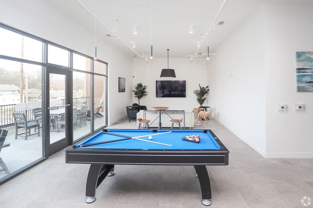 an apartment clubhouse with a tv, pool table, and chairs