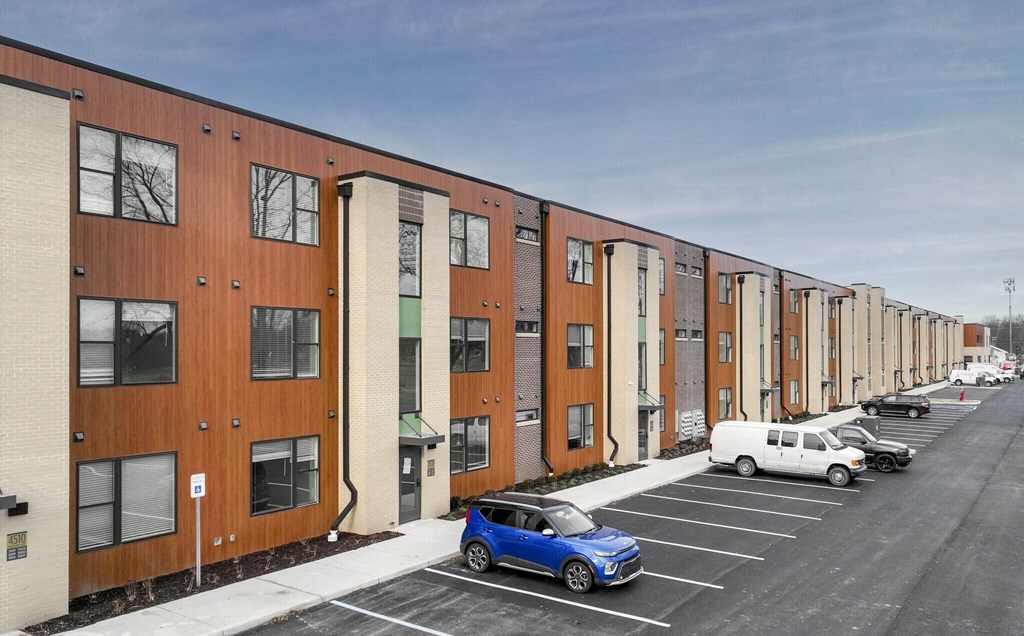 a row of apartment buildings with cars parked in front of them