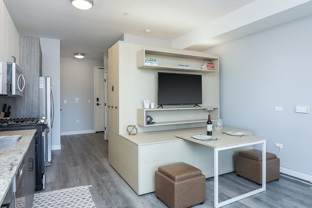 A kitchen with a table and chairs in front of a fridge.
