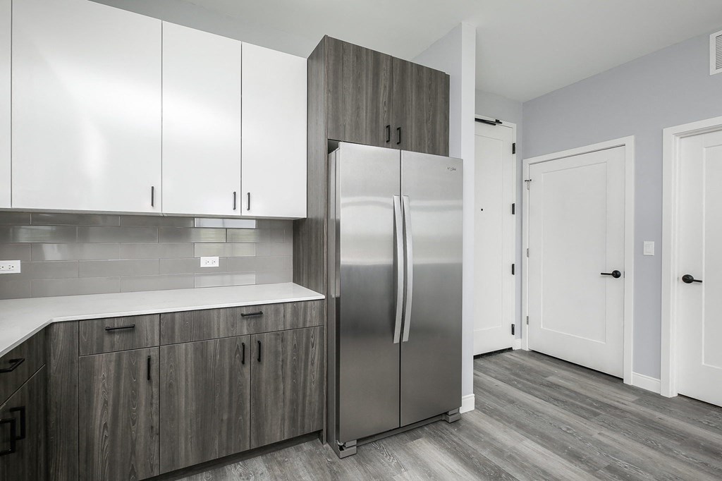 a kitchen with white cabinets and a stainless steel refrigerator
