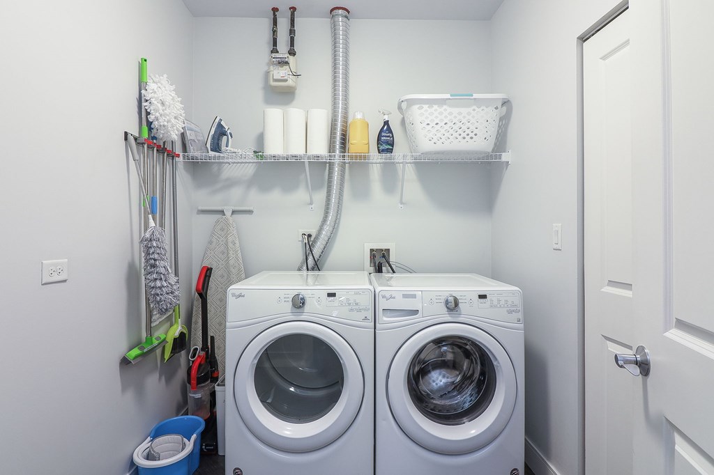 A small laundry room with two washing machines and a white door.