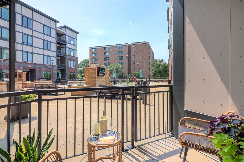 A balcony with a table and chairs overlooking a courtyard.