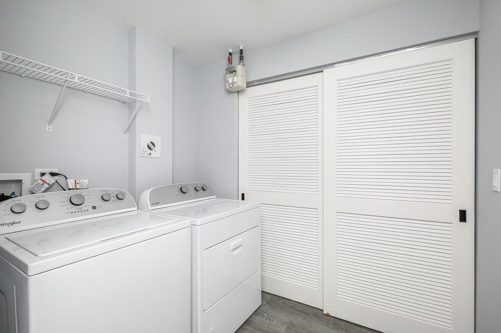 a white laundry room with white appliances and a white closet