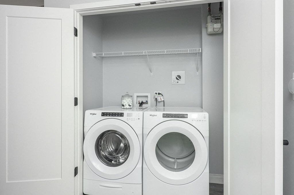 Two white front load washing machines in a white cabinet.