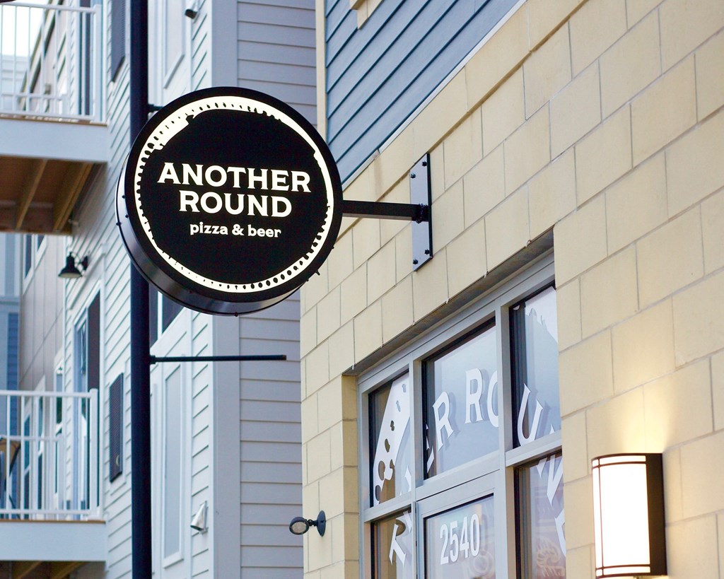 a sign for another round pizza and beer on the side of a building