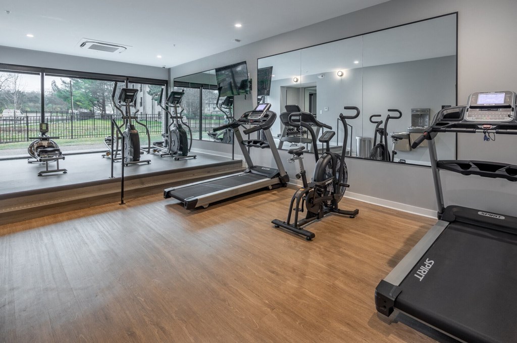 a gym with treadmills and other exercise equipment on a wooden floor