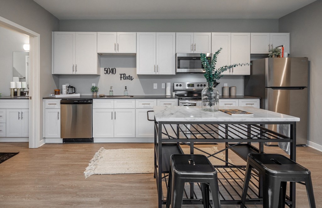 a kitchen with white cabinets and a table with black stools