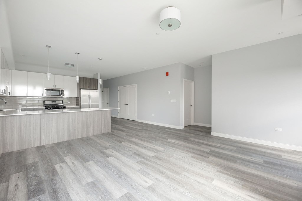 a renovated living room and kitchen with white walls and wood floors