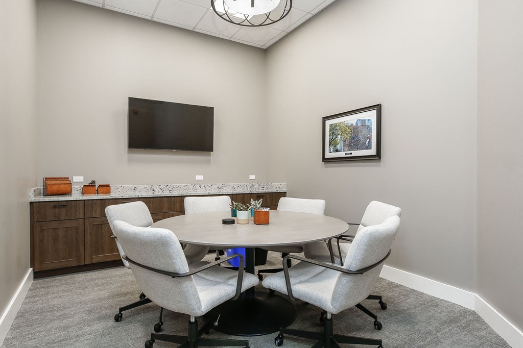 a conference room with a table and chairs and a television