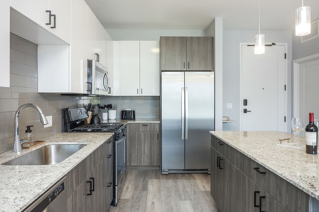 A modern kitchen with a stainless steel refrigerator and black stove.
