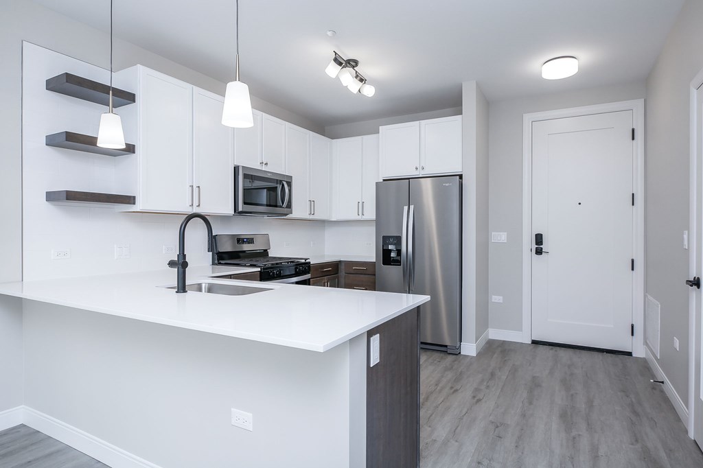 A kitchen with white cabinets and a stainless steel refrigerator.