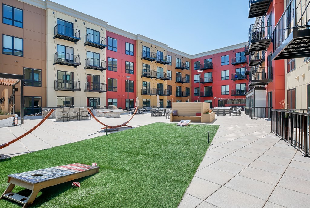 a courtyard with a hammock and a picnic table in front of an apartment building