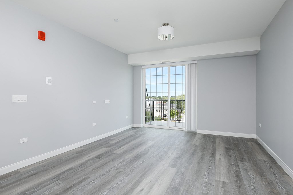 A room with a grey floor and white walls with a window and a balcony.