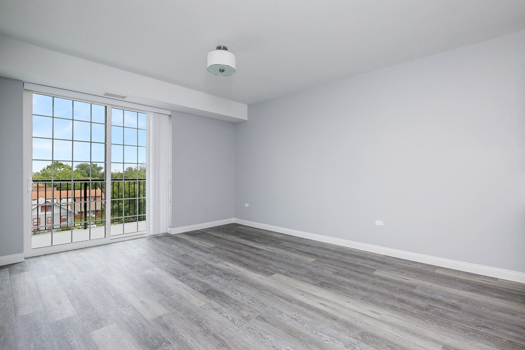 an empty living room with wood flooring and a balcony