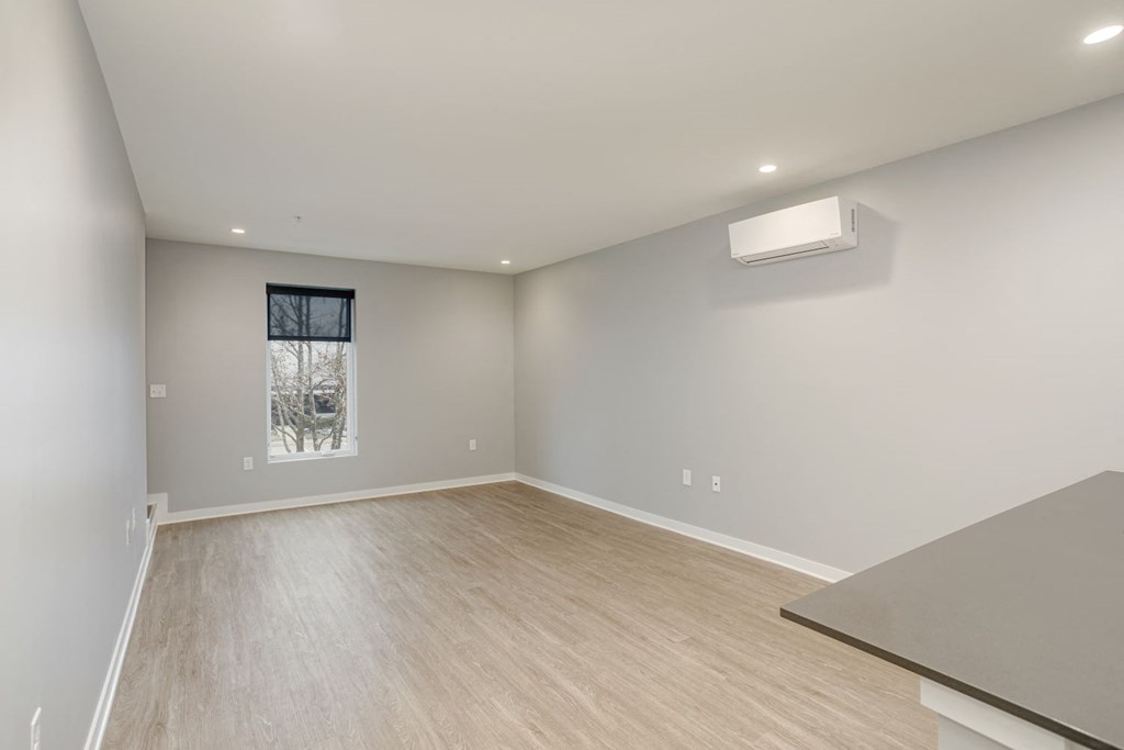 a living room with white walls and wood flooring and a window
