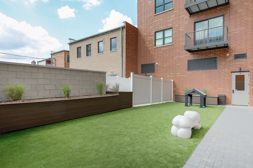 the back yard of a house with artificial grass and a fence