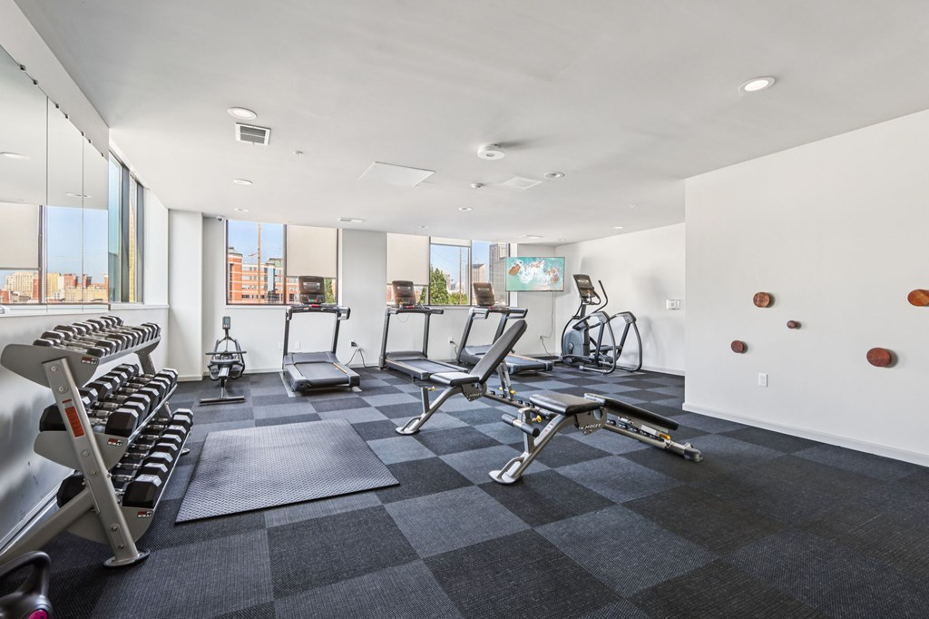 A gym with a variety of equipment including treadmills, weights, and exercise bikes.