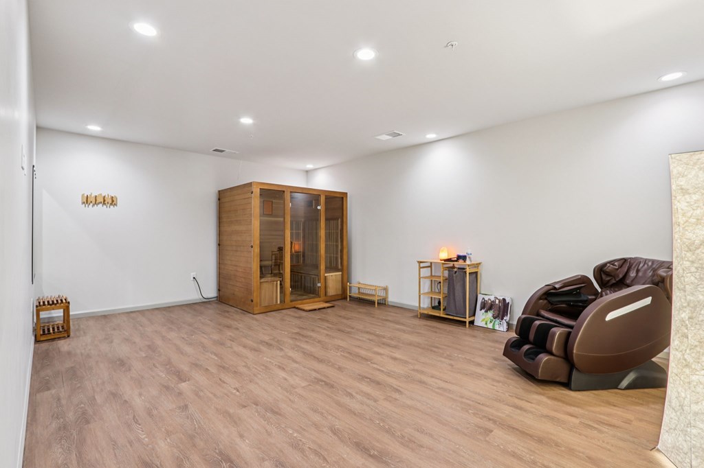 A room with wooden flooring and furniture including a couch and a cabinet.