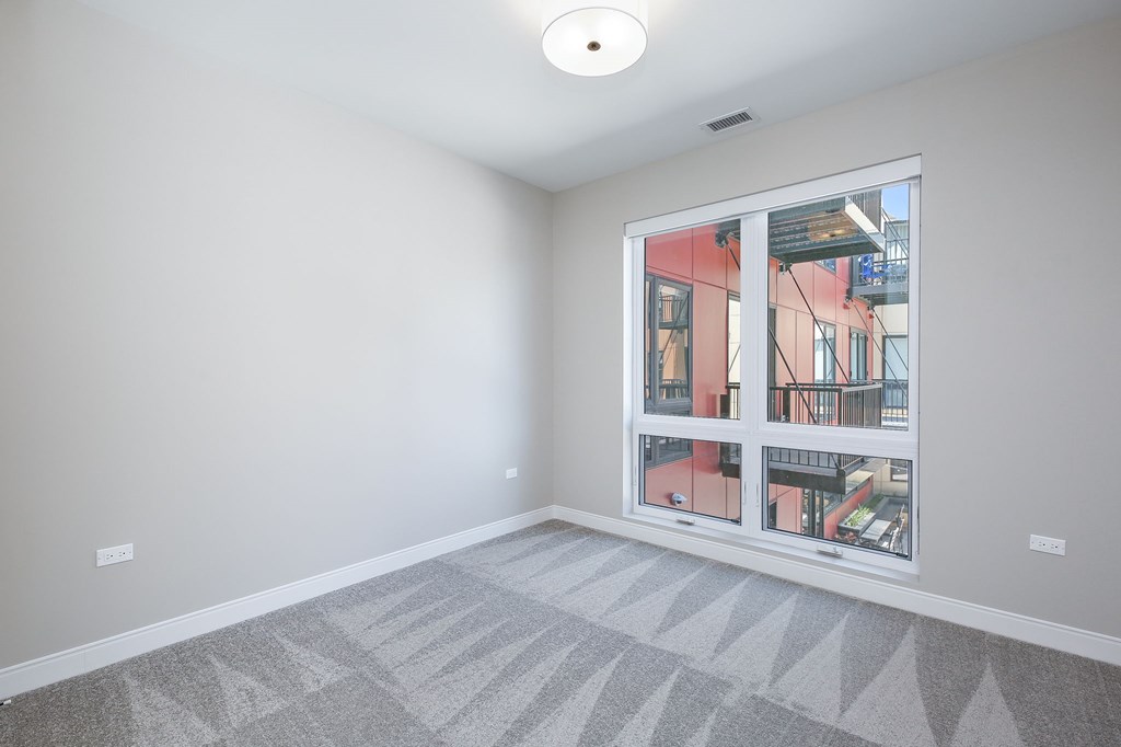 A room with a large window and a grey carpet.