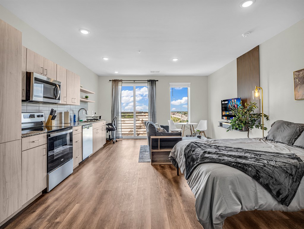 a bedroom with a bed and a kitchen and a living room