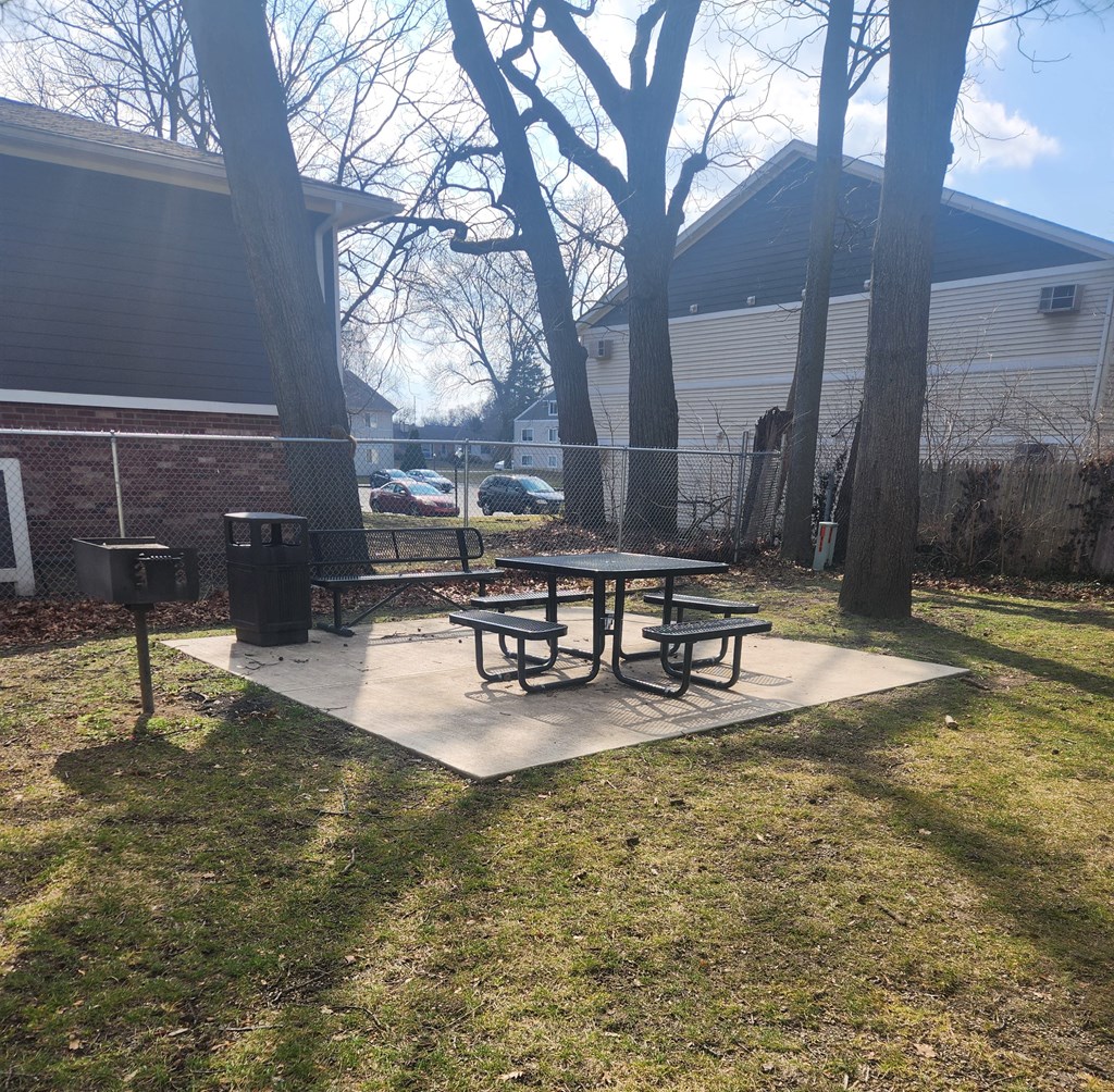 a picnic table in a park next to a fence