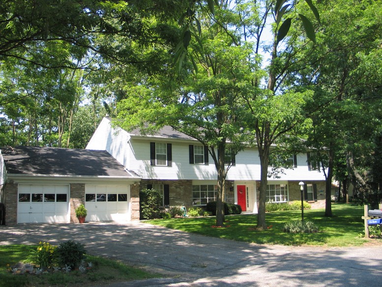 a white house with a red door and trees