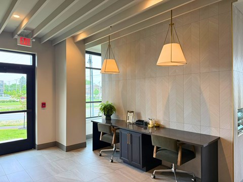 A modern office space with a desk, chairs, and a hanging light fixture.