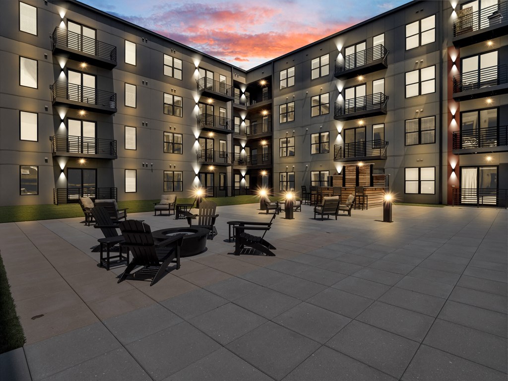 an exterior view of an apartment building at dusk with tables and chairs