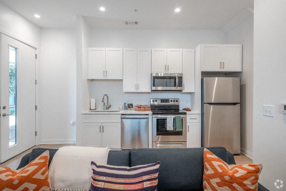 a living room with a couch and a kitchen with stainless steel appliances