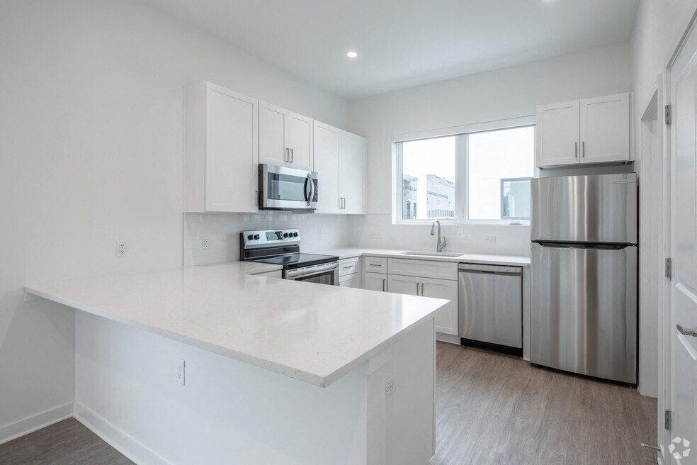 a white kitchen with stainless steel appliances and white counter tops