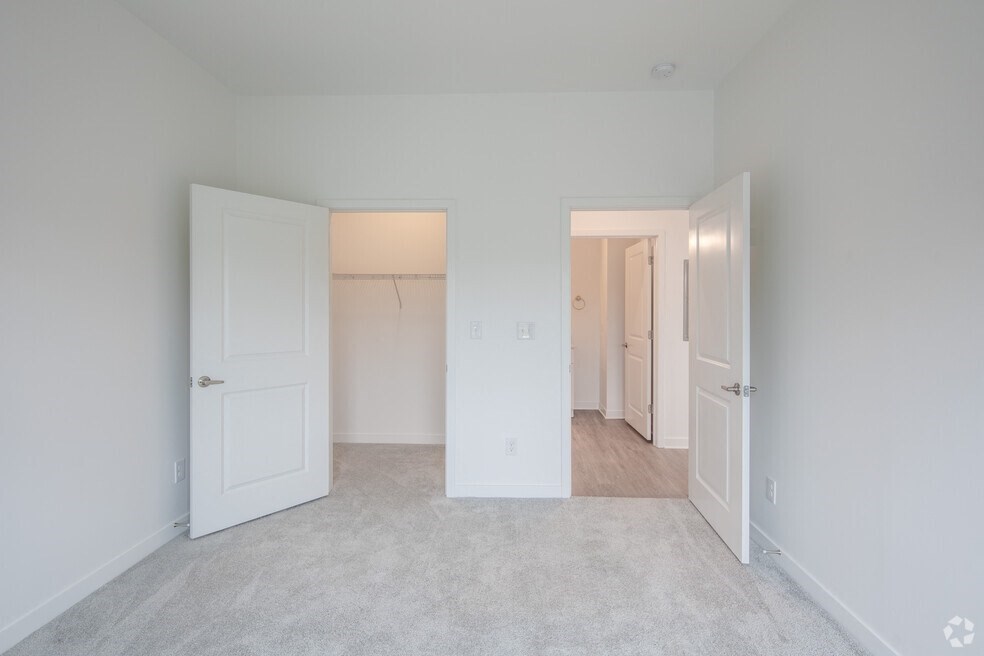 an empty bedroom with white doors and a closet