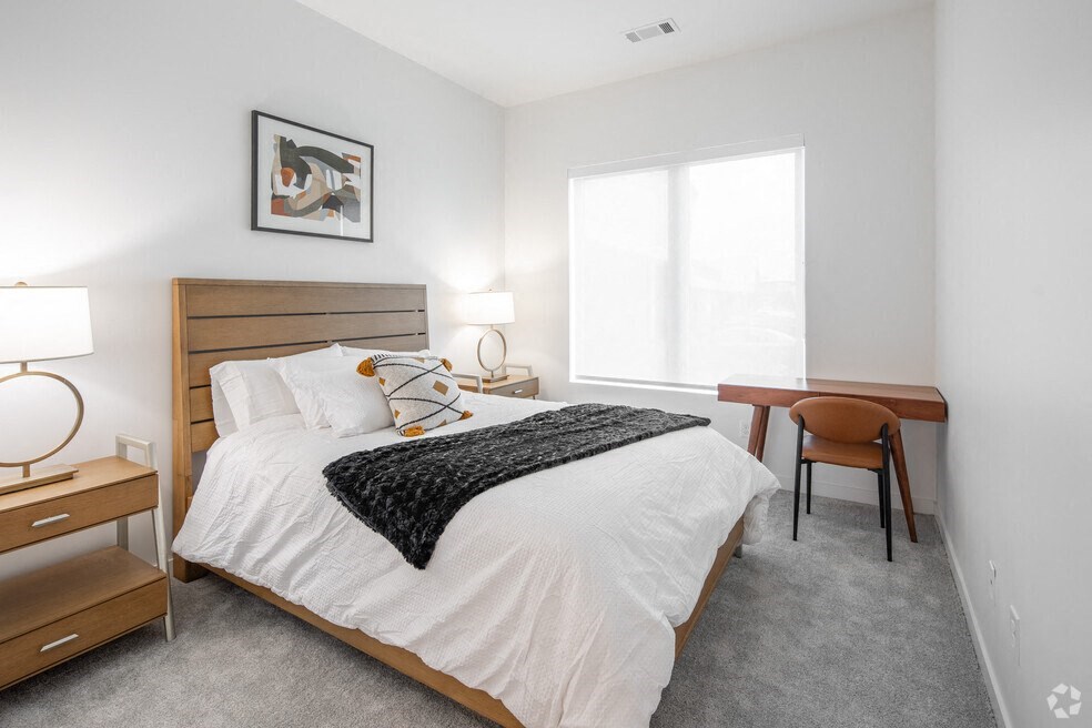 a bedroom with a bed and a desk and a window