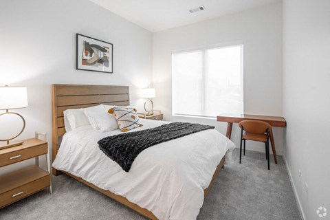 a bedroom with a bed and a desk and a window