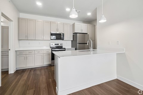 A modern kitchen with wooden floors and white appliances.
