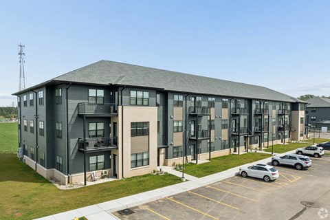 A large grey building with a parking lot in front.